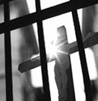 Black and white, cross seen through prision bars with divine light shining down.