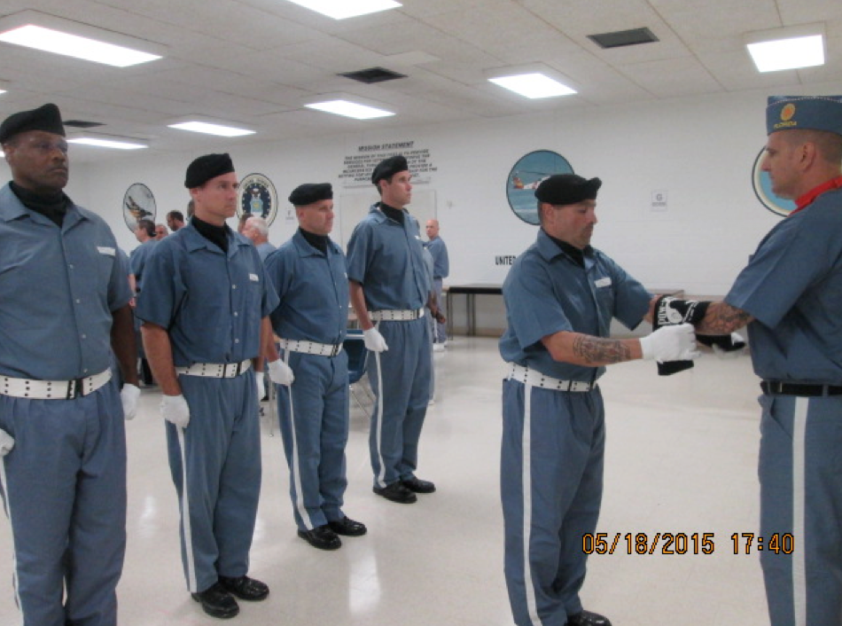 Several veterans dressed in blue and white, black berrets on their heads, and performing a ceremony.